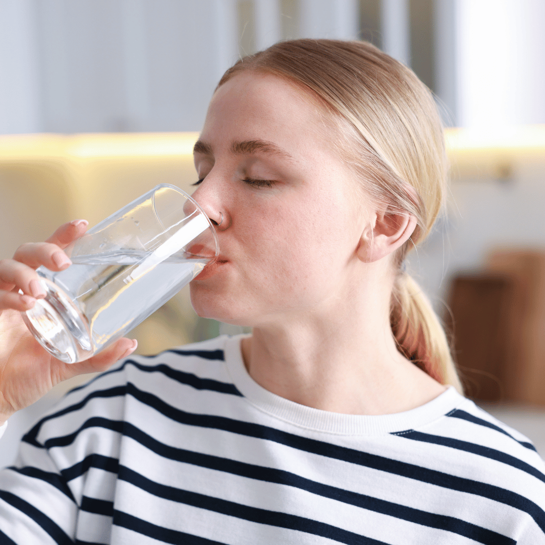 Image of woman drinking cold water to help stay cool at home in hot weather